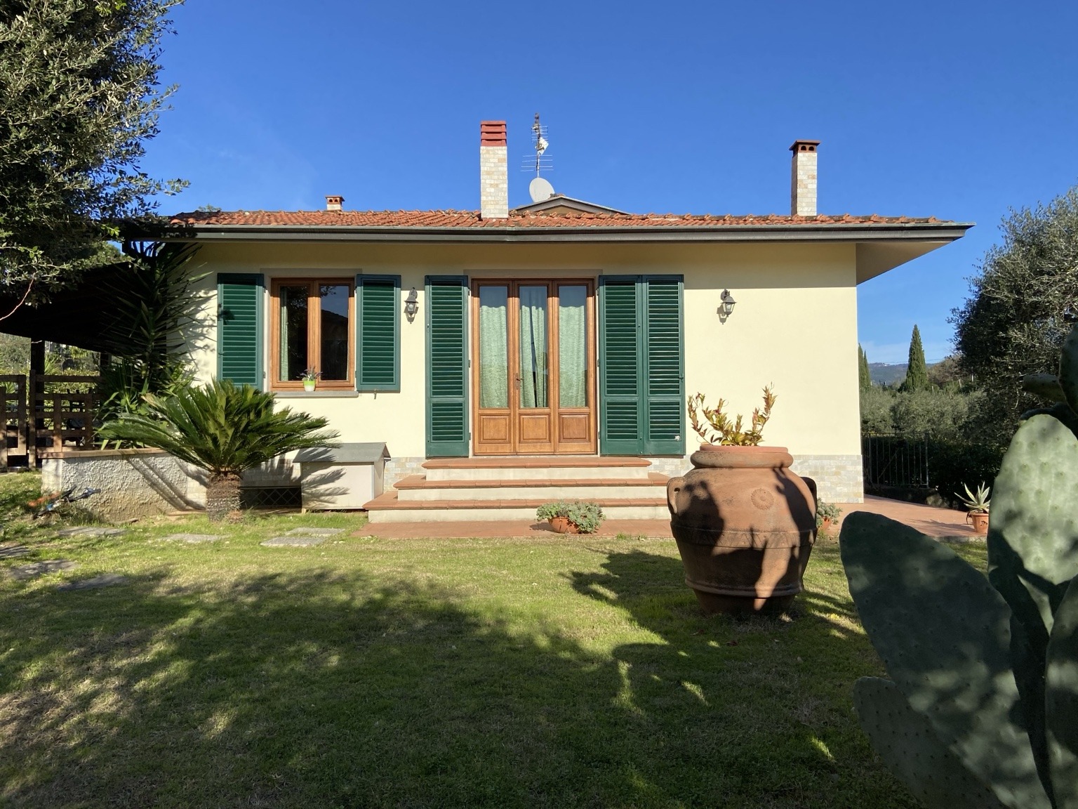 Facciata della villa con persiane verdi e accesso dal giardino